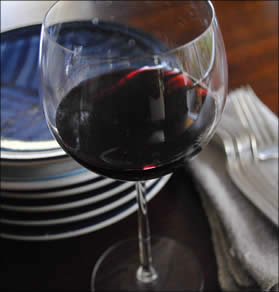Glass of Dolcetto with plates and silverware