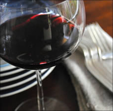 Glass of red wine with plates and silverware.