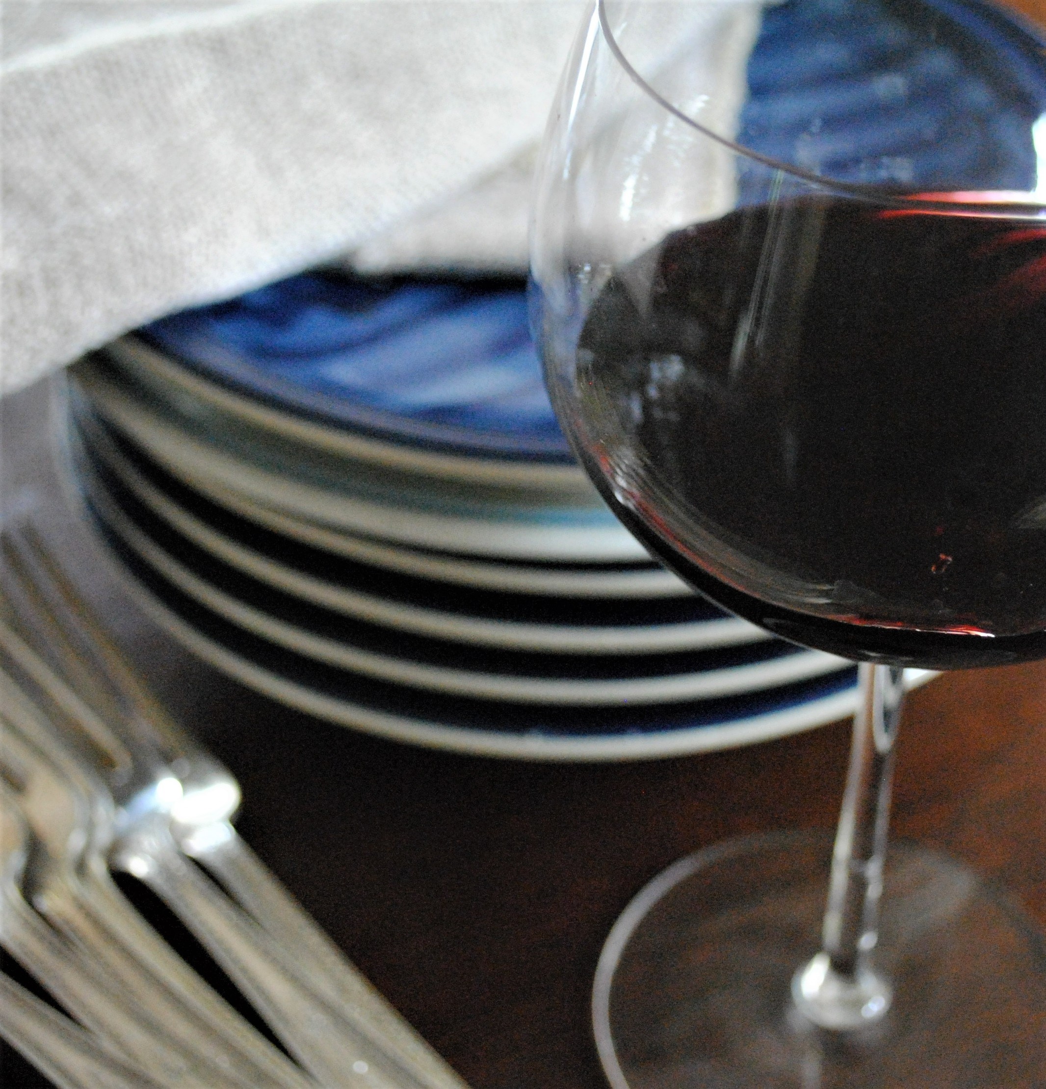 Red wine glass with plates and silverware.