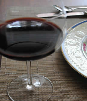 Glass of red wine with formal china place setting